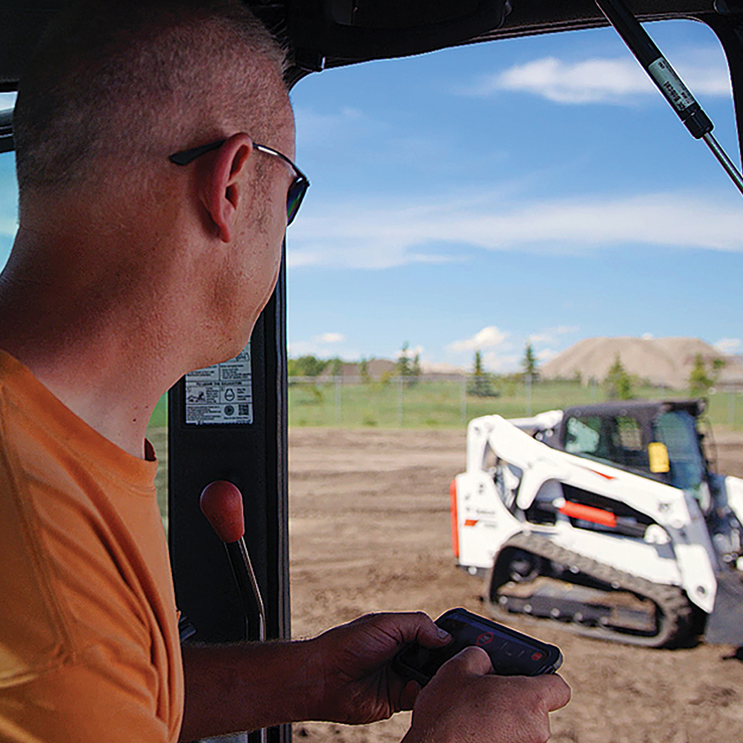 Man operates Bobcat compact track loader remotely 