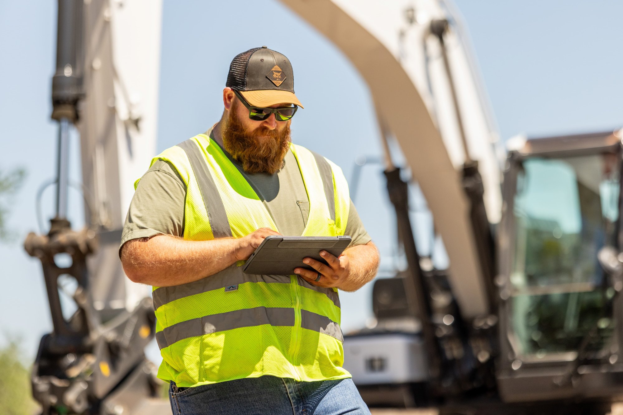 Operator on tablet in front of Bobcat E220 large excavator
