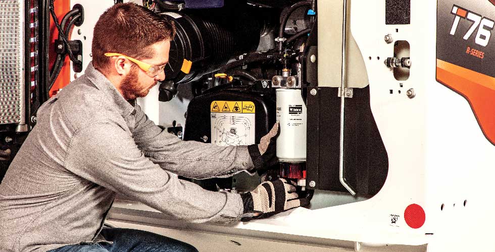 A man in safety glasses and gloves fixes a machine