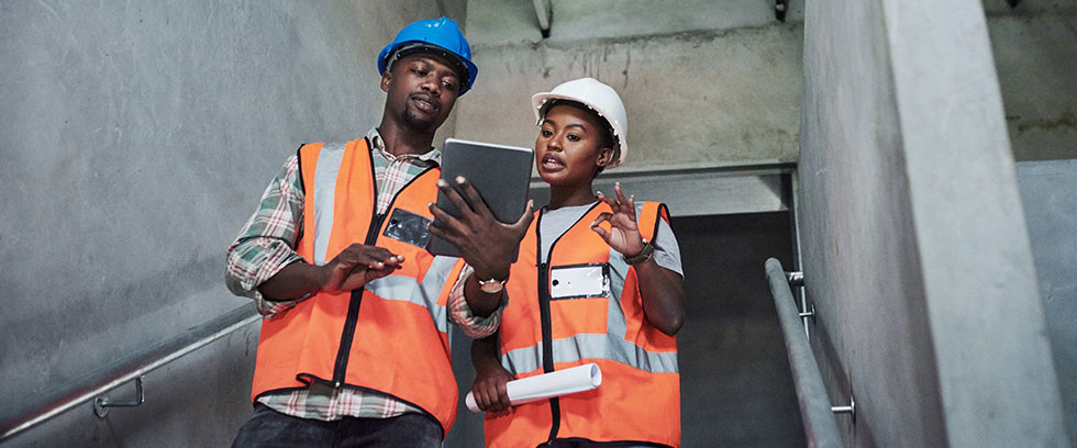 two construction workers looking at tablet and discussing