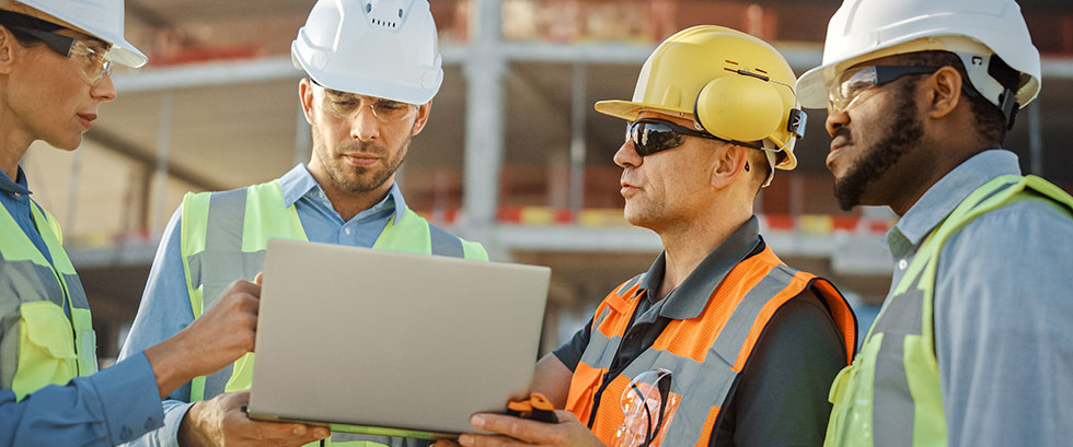 Four construction workers looking at laptop
