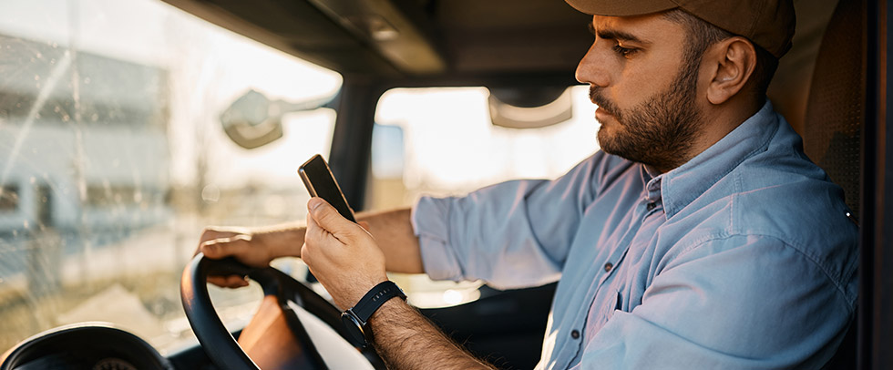 A man looks at his phone while driving