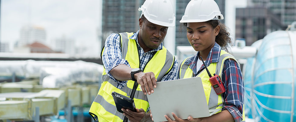 Two construction workers looking at computer