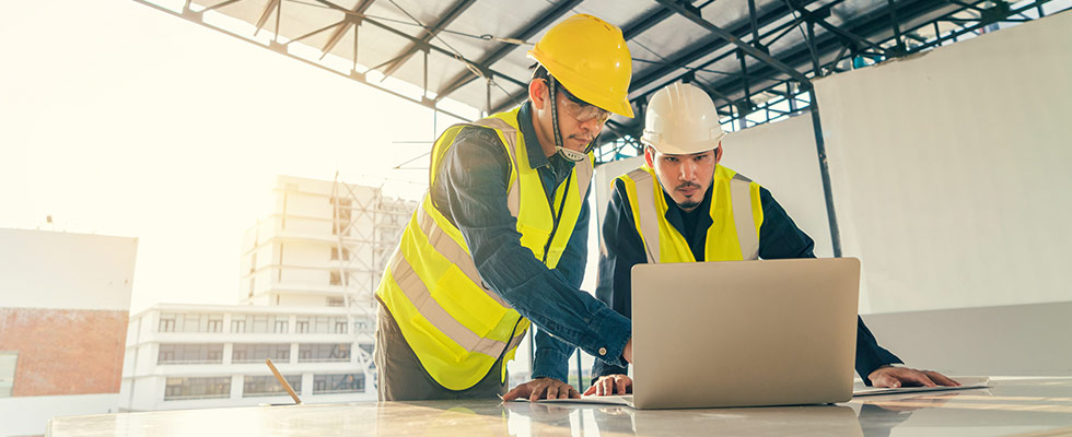 Two construction workers using laptop