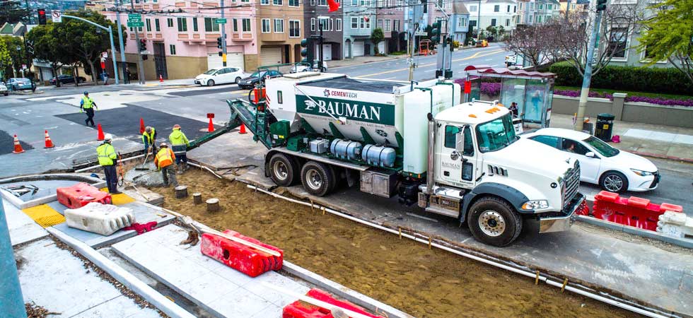 Five men work on a construction site with a large cement truck