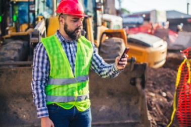 Construction worker checks cell phone