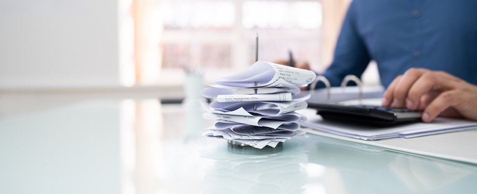 Person using calculator with stack of receipts in front of them