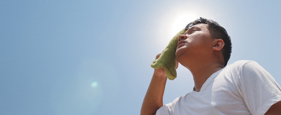 A man looks up and wipes his forehead with a towel