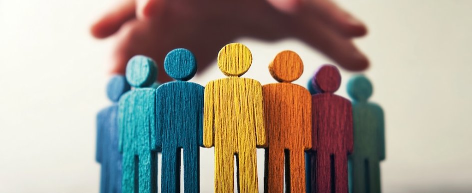 Colorful wooden figures under protective hand