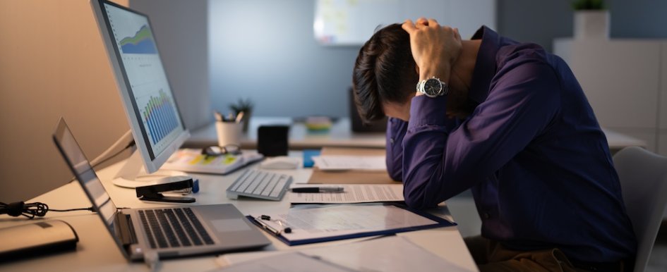 Man stressed at work with head in hands