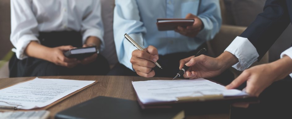 People signing documents at meeting table