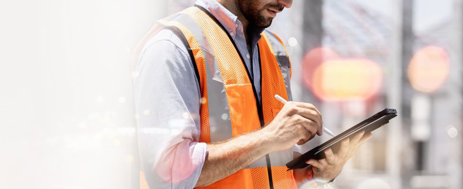 Man in construction vest using tablet, with tech concept background
