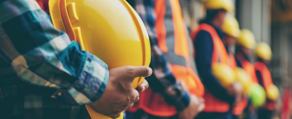 line of construction workers holding hard hats