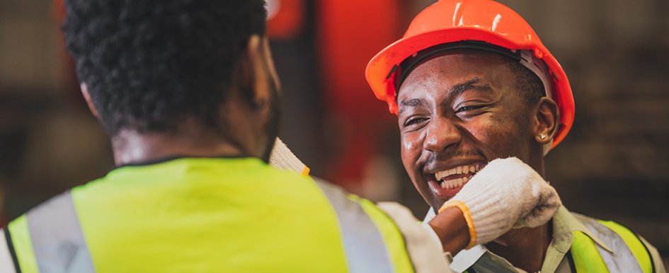People in vests and hard hats smiling/Adobe Stock