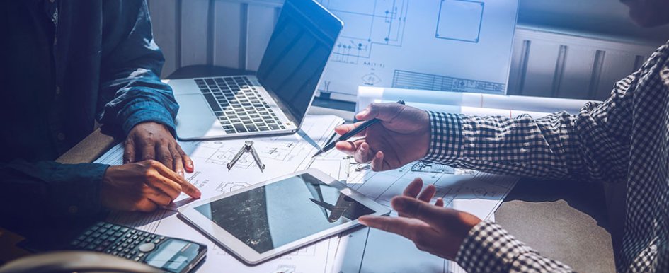 two workers pointing to tablet and laptop