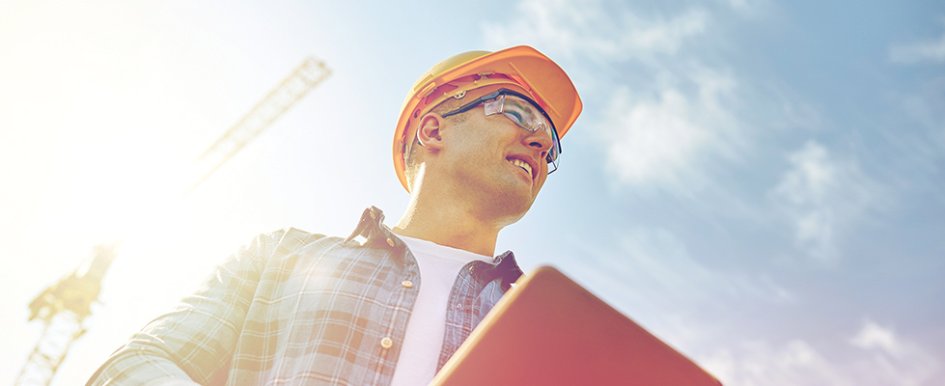 Construction worker in hard hat and goggles smiling on the jobsite