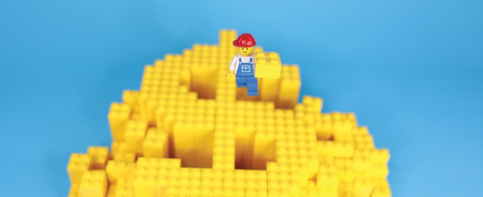 Lego blocks in the shape of a dollar bill with a Lego construction worker on top / Adobe Stock