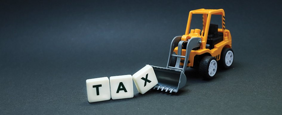 wheel loader scooping up blocks spelling "tax" 