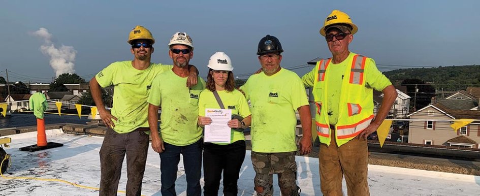 Kara McCaffrey holding a toolbox talk with a roofing crew at Houck