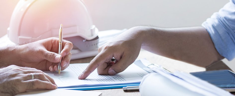 Two people looking at papers with hardhat in background