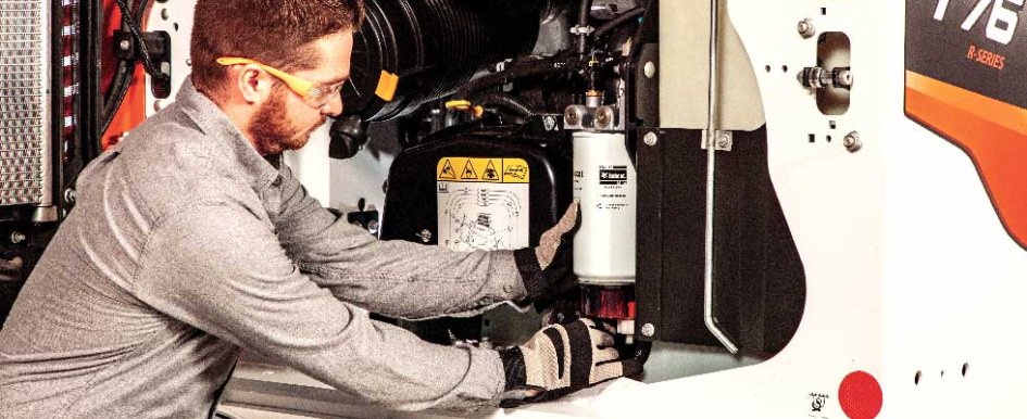 A man in safety glasses and gloves fixes a machine