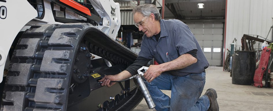 Man checking Bobcat machine's tracks/Bobcat