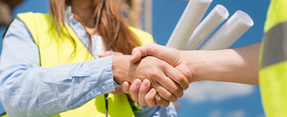 Two individuals in bright safety vest shake hands