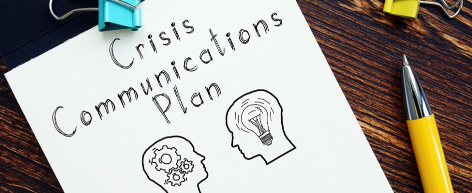 Piece of paper with "crisis communications plan" written on it and illustration of heads with gears and lightbulbs