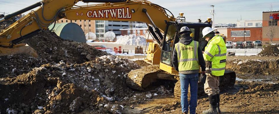 Two construction workers on jobsite in front of S.J. Cantwell machine