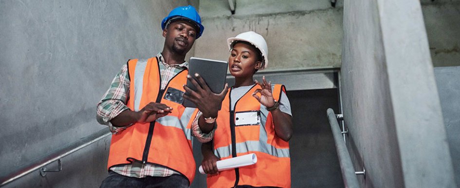 two construction workers looking at tablet and discussing