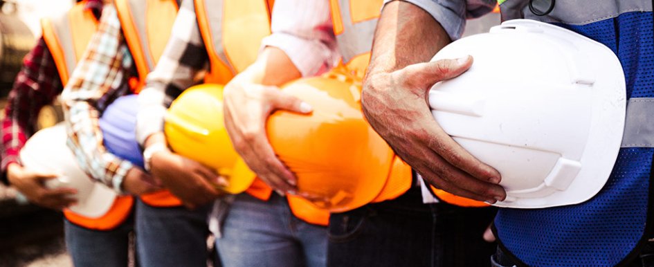 5 workers in a line holding hardhats