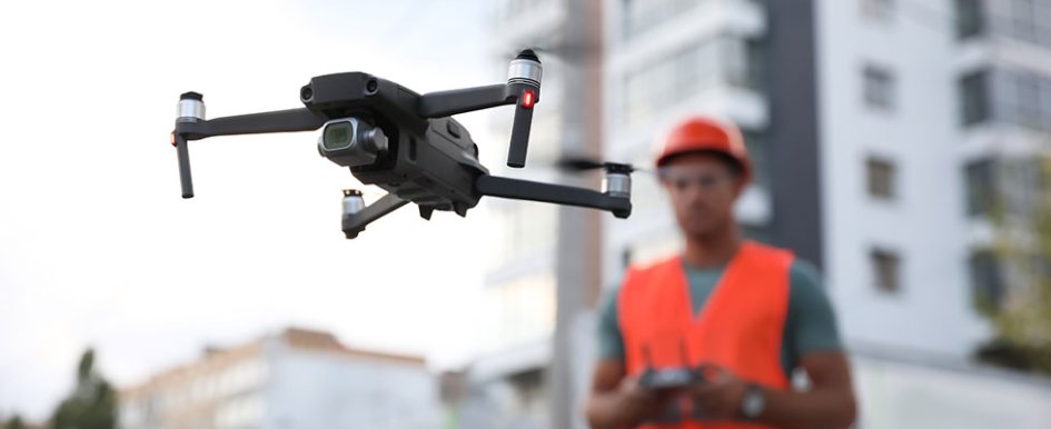 A construction worker in bright safety gear flies a drone