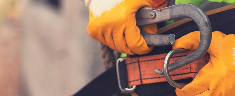 Worker attaching safety harness to show construction worker safety 