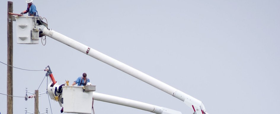 Utility workers in buckets, working on lines