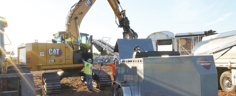 Worker in vest and hard hat with hand on heavy equipment