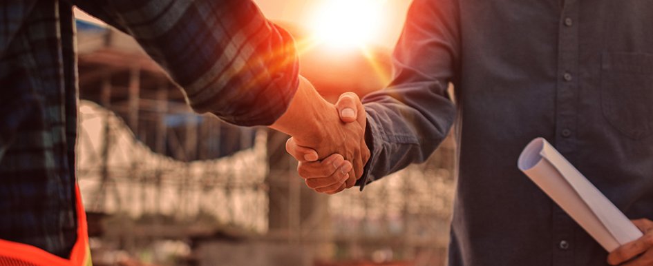 Two people shaking hands; one person holds blueprint; sun shines above handshake