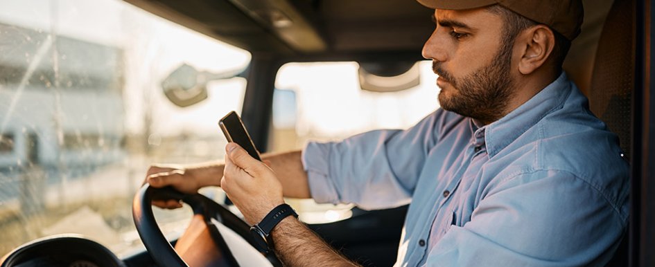 A man looks at his phone while driving