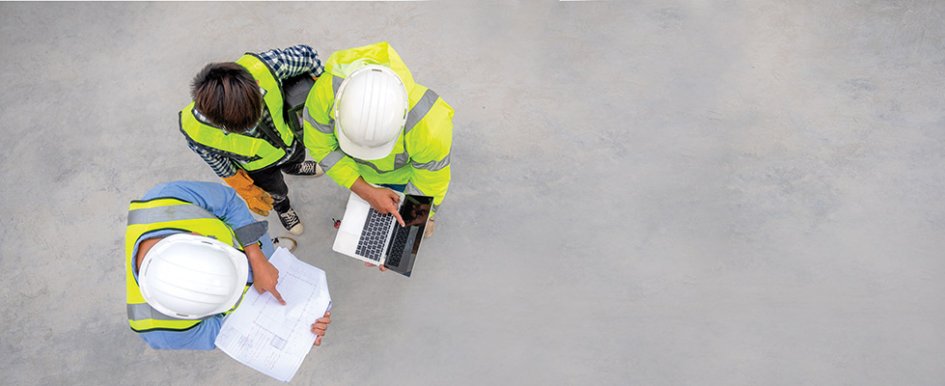 Three people in hard hats and vests talking and looking at files