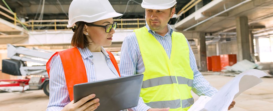 Two workers looking at paper and tablet