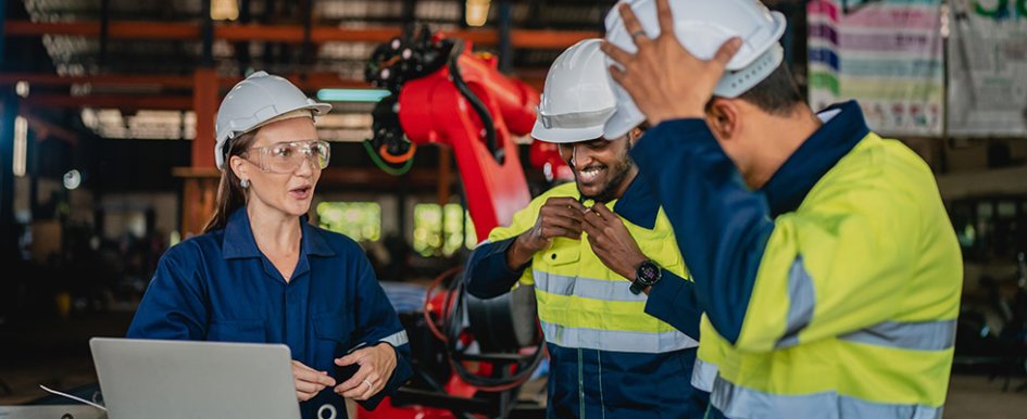 Three workers in hard hats and PPE in conversation