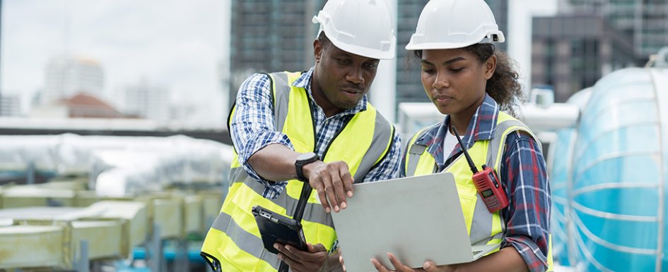 Two construction workers looking at computer