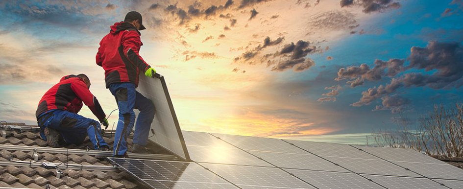 Two workers on roof laying solar panels