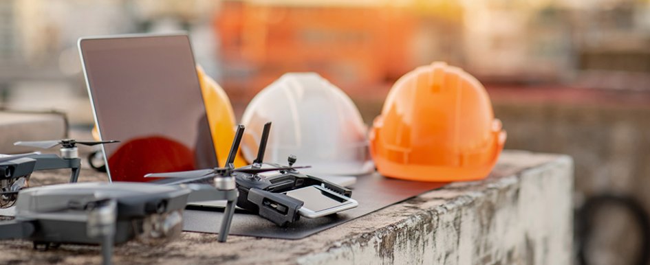 3 hard hats on table with laptop & tech