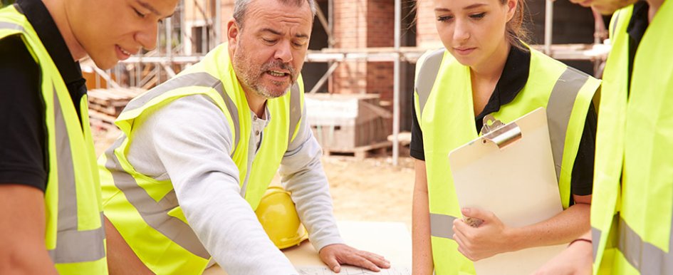 People in construction vests looking at plans together