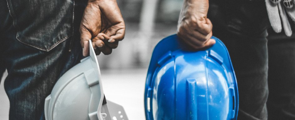 Two hands holding hardhats