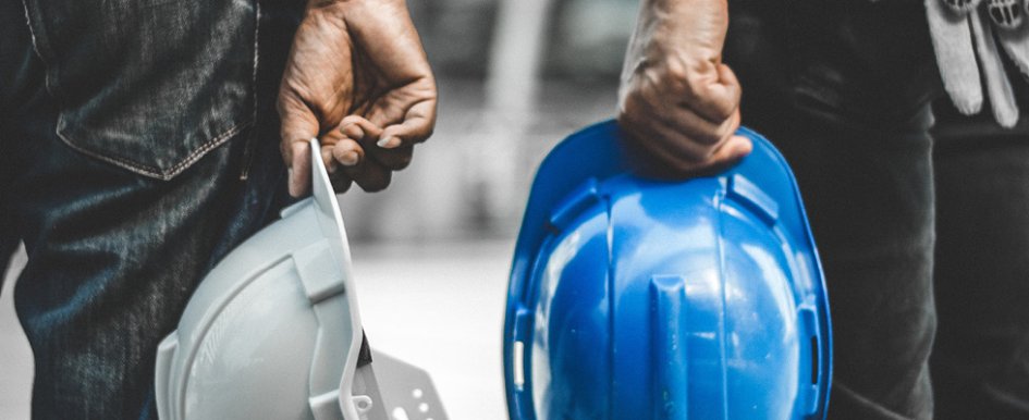 Two hands holding hardhats