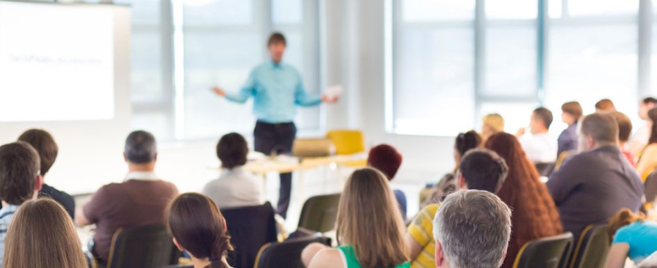 A classroom full of adult students watches a presentation