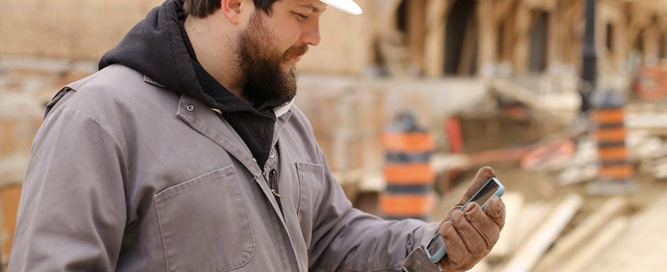 A man in a hard hat looks at his phone