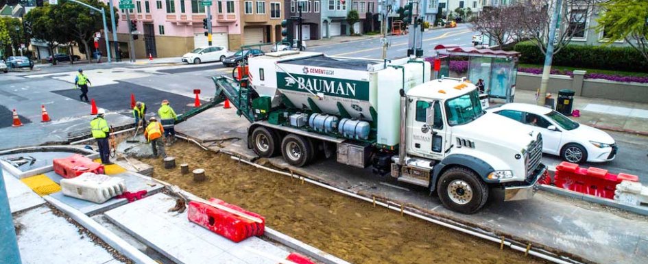 Five men work on a construction site with a large cement truck