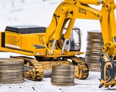 Toy excavator by rows of coins to represent construction financial options